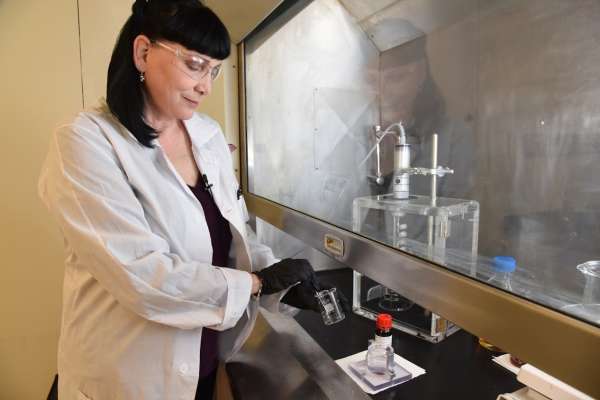 Catherine Riddle stands in front of a fume hood at INL and does science!