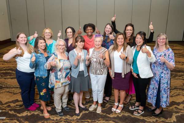 The U.S. WIN Steering Committee poses for a group photo, and all the women in the group give a thumbs up to the camera