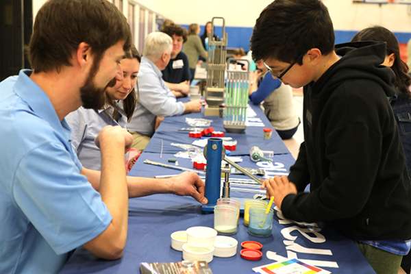 Employees from Framatome in Richland, Washington, help a participant in Kids Engineering day make a pretend nuclear fuel pellet.