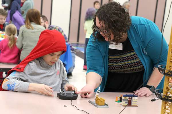 Crystal Slavens, Energy Northwest U.S. WIN chair, shows a Kids Engineering Day participant how to use a remote control crane.